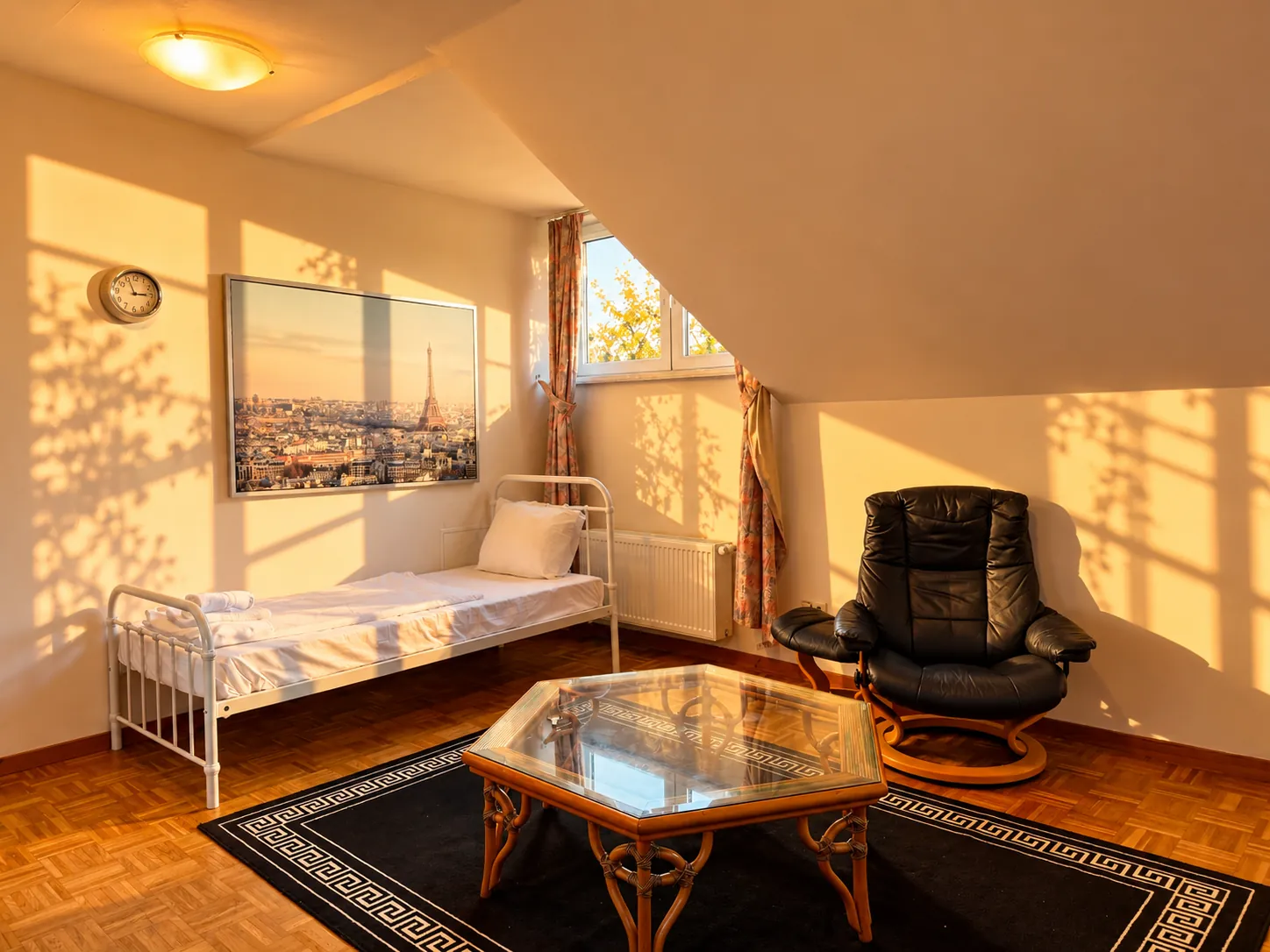 Dachzimmer mit Einzelbett, Sessel und Couchtisch